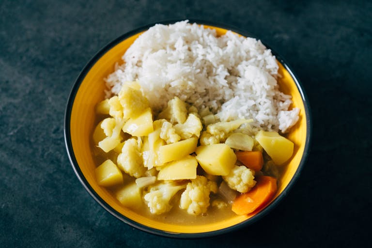 A vibrant bowl of vegetable curry with rice, showcasing comforting homemade flavors.
